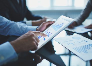 Image of businessperson pointing at document in touchpad at meeting